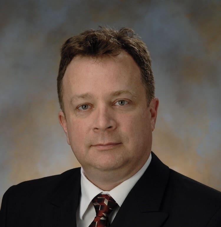 A man in suit and tie standing next to a wall.